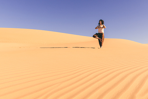 Yoga meditation on the sand dune,healthy female body in peace, woman sitting relaxed on sand, calm girl enjoying nature, active vacation lifestyle, Zen spa, wellness concept