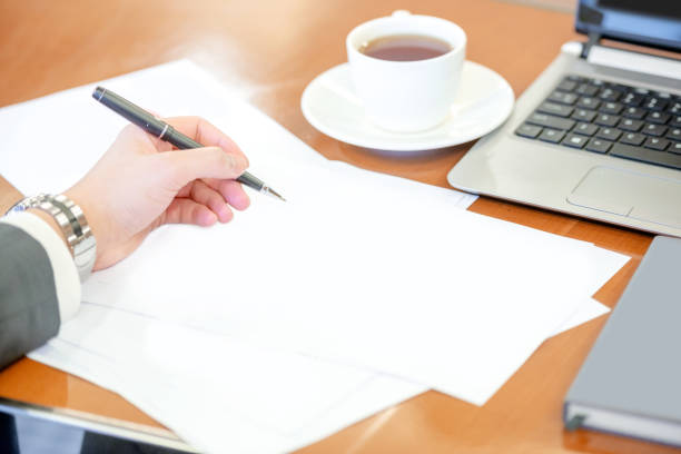 istock Businessperson holding pen with empty paper 1211302071