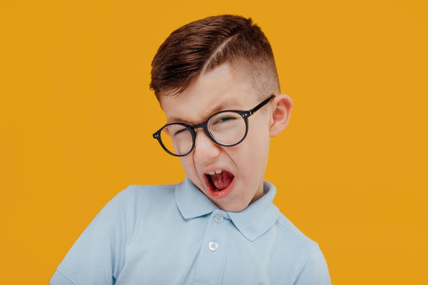 istock little boy in glasses grimace. isolated on yellow background 1211303682