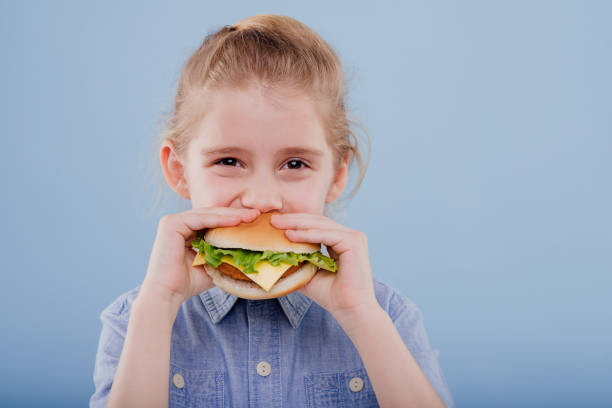 istock close up, kid eats a sandwich. profile view, isolated on blue background, copy space 1211303705