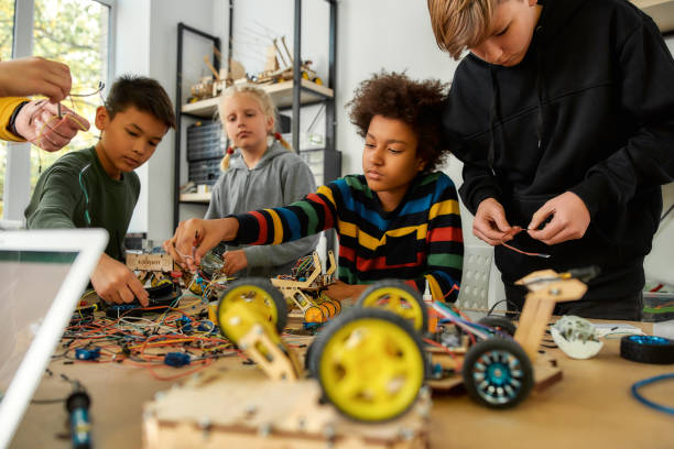 istock First Attempts In Learning. Diligent girl and boys making a vehicle at a technology class. Smart kids and STEM education. Selective focus 1211307597