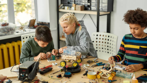 istock Giving solutions. Three kids building robots and vehicles at robotics lesson. Smart children and STEM education. 1211308475