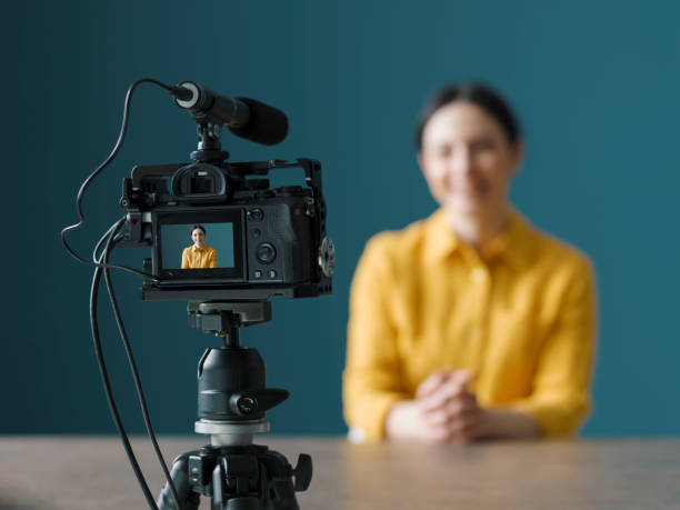 vlogger profesional sentado frente a una cámara - compartir fotos fotografías e imágenes de stock