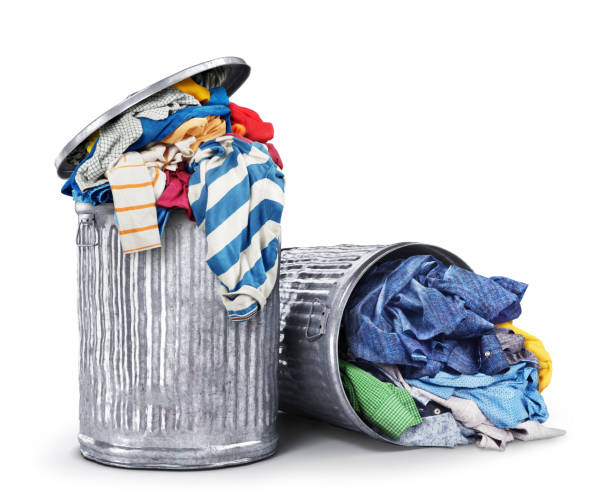 Heaps of clothes in iron dumpsters isolated on a white background. Consumption concept.