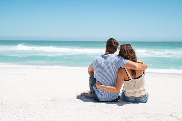 istock Couple embracing and sitting on beach 1211312551
