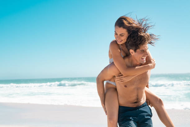 愛するカップルはビーチで夏を楽しむ - swimwear caribbean sea beach water ストックフォトと画像