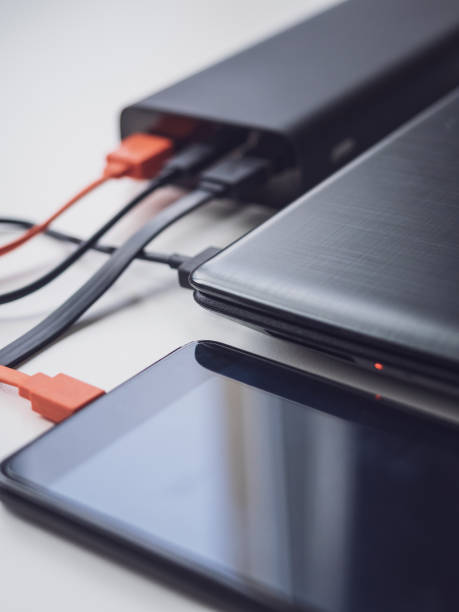 Power bank charges your laptop and phone using different cables. Simultaneous charging of different devices. Modern innovative technologies. Vertical image
