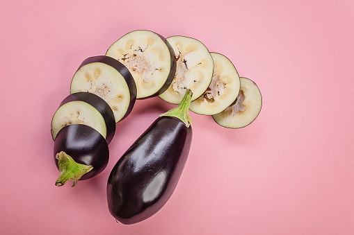 Close-up ripe purple eggplant on a pink background. Top view. Copy space