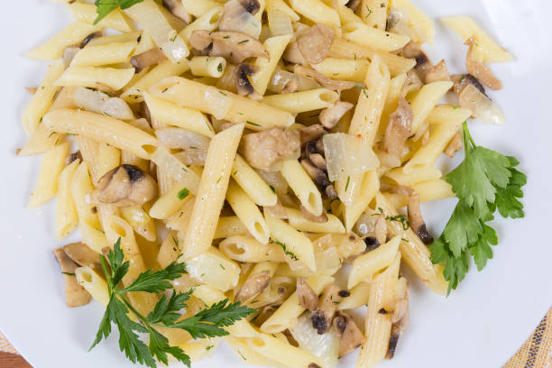 istock Cooked penne pasta with fried mushrooms and onions, top view 1211318509