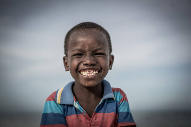 garçon noir sur la plage - africa child village smiling photos et images de collection