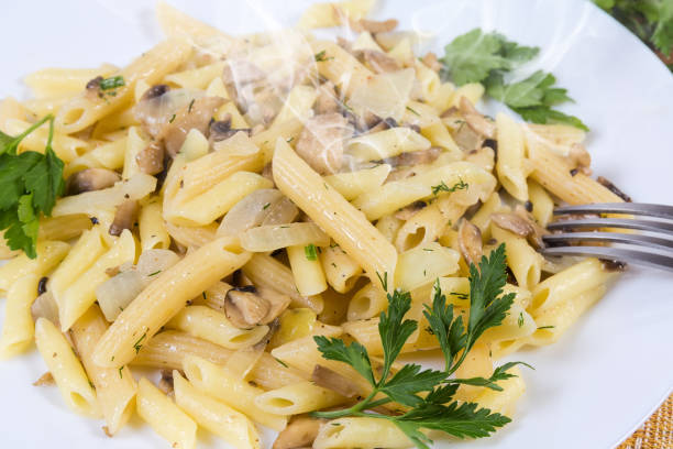 istock Cooked penne pasta with fried mushrooms and onions close-up 1211319905