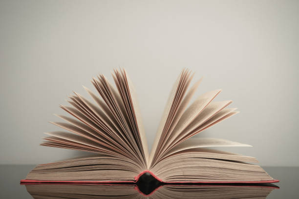 istock Beautiful open book on a gray and glass table background. 1211319964