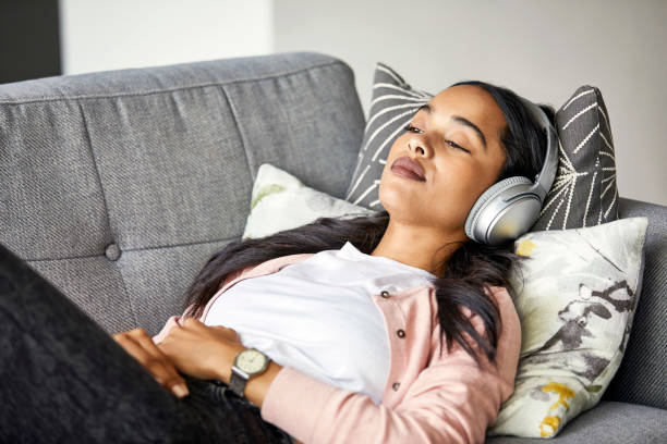 istock Woman listening music while lying on sofa at home 1211322028