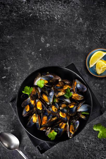 istock Vertical shot of cooked mussels on black background 1211322764