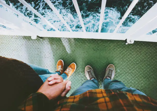 Couple in love Man and Woman feet holding hands standing together above sea Traveling by ship family lifestyle concept romantic vacations cruise journey