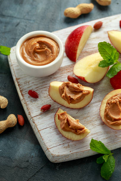 istock Peanut butter and apple to snack. on white wooden board 1211322842