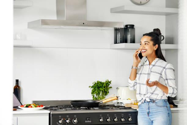 istock Smiling woman talking on mobile phone in kitchen 1211324794