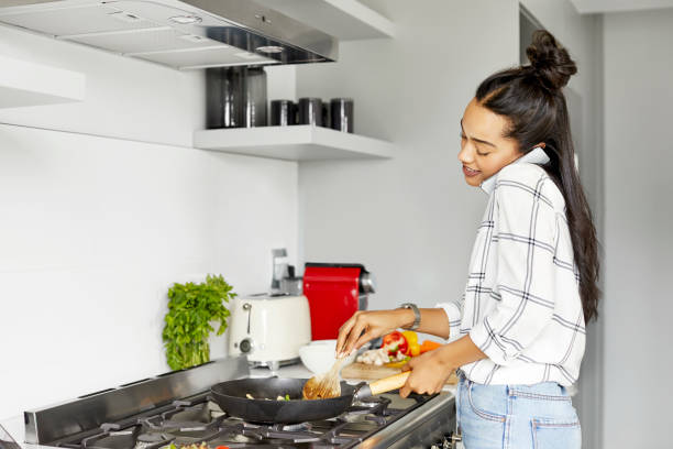 istock Woman talking on smart phone while cooking food 1211324801