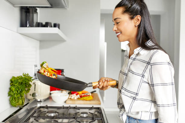 Smiling woman tossing vegetables in kitchen