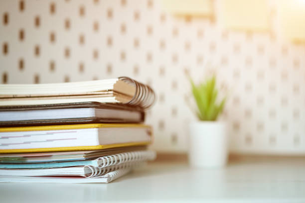 istock Desktop stack of notebooks and  flower in the background, soft focus 1211327047