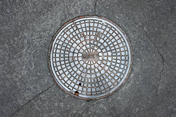 Manhole cover An old sewer manhole cover surrounded by an asphalt street manhole stock pictures, royalty-free photos & images