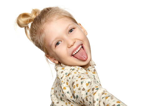 Portrait of funny little girl showing her tongue, isolated over white background with copy space.