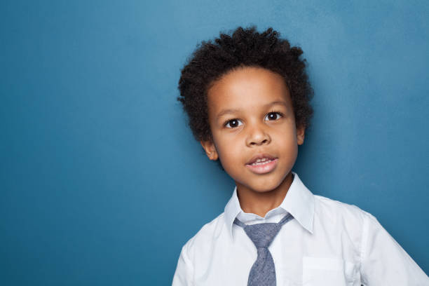 istock Little black child boy smiling and looking up on blue background 1211331180