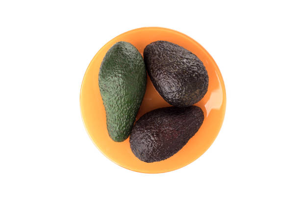 istock Avocado fruits on an orange plate over white background. 1211335552