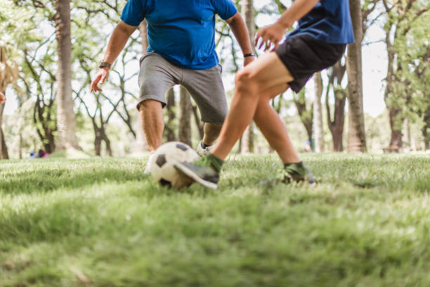 istock Father and sons playing soccer in the park 1211338358