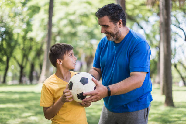 istock Father and son playing soccer in the park 1211338396