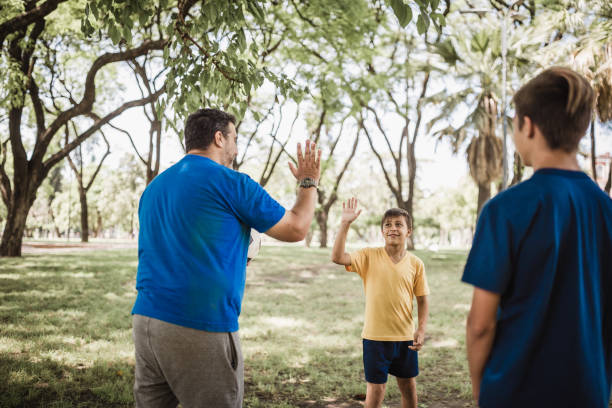 istock Father and sons playing soccer in the park 1211338450