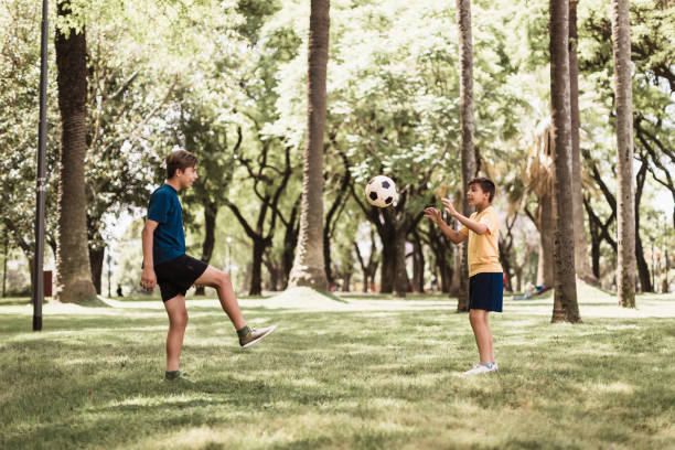istock Brothers playing soccer in the park 1211338452