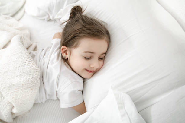 istock A cute little girl is sleeping in a white bed . 1211340648