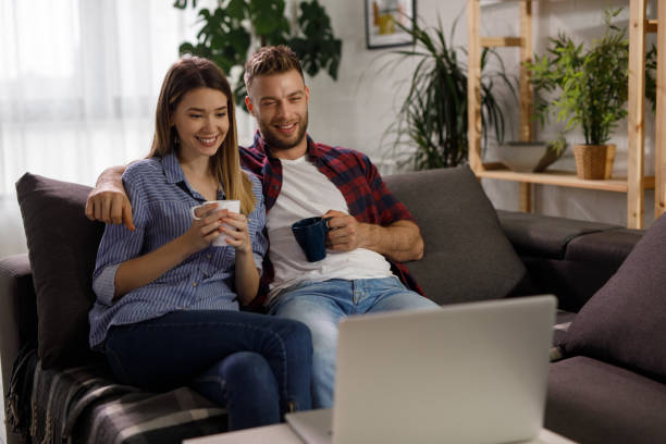 istock Young couple using a laptop while relaxing on the sofa at home 1211341537