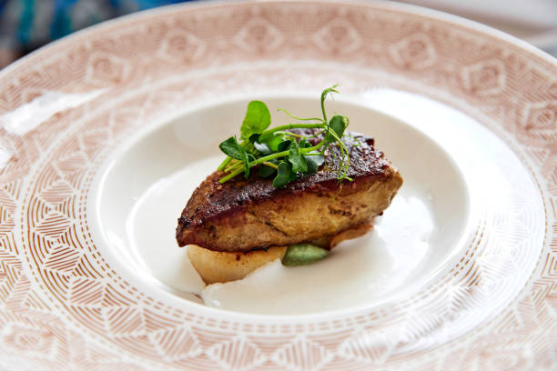 istock Foie gras scallops decorated with greens in sauce on plate with patterns 1211343083
