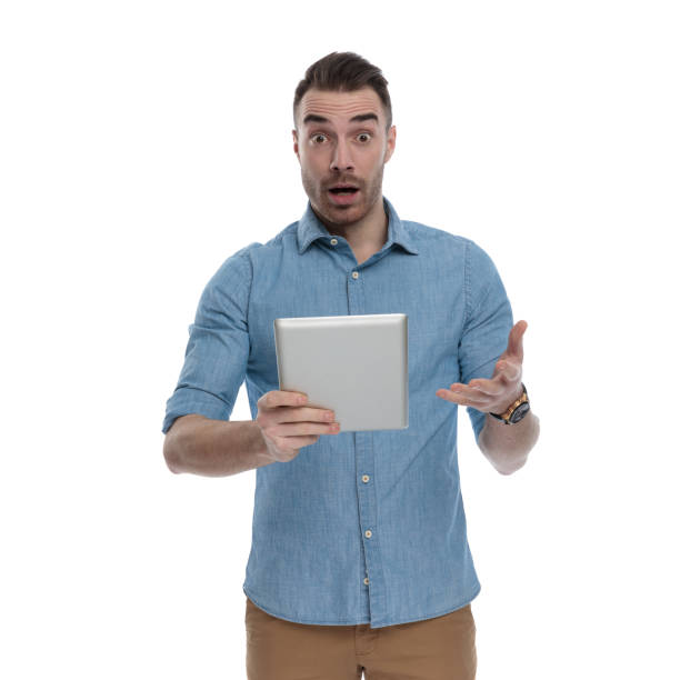 istock Amazed casual man holding tablet and gasping 1211343338