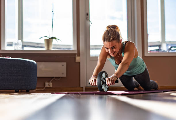 Sports woman is doing ab roller exercise while working out. stock photo