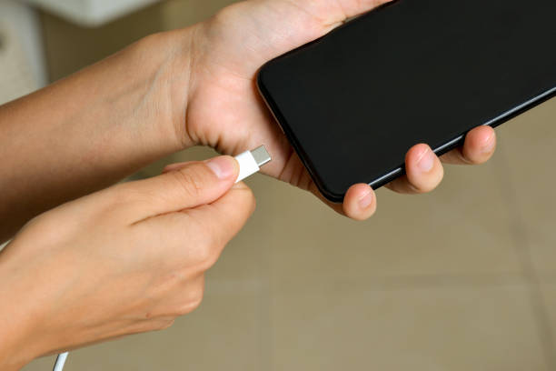 istock Woman plugging a charger in a smartphone 1211344619