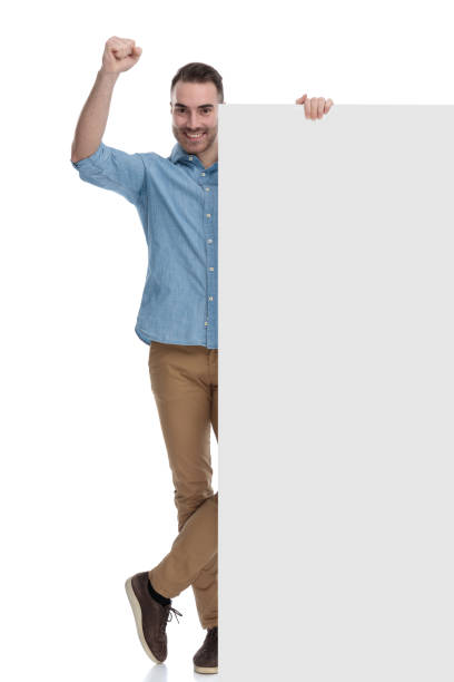 istock Cheerful casual man celebrating and holding blank billboard 1211344725