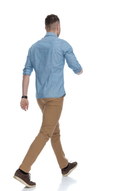 istock Rear view of casual man walking while wearing blue shirt 1211344890