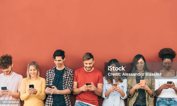 Group Young People Using Mobile Smartphone Outdoor Millennial Generation Having Fun With New Trends Social Media Apps Youth Technology Addicted Red Background Stock Photo - Download Image Now