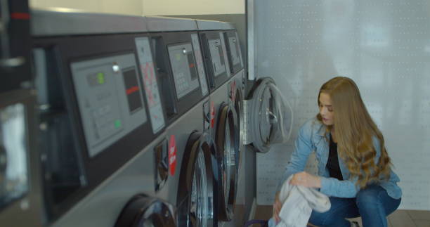 istock Womam is putting colourful laundry into washing machine. Meanwhile clothes are drying and spinning in the dryer. 1211346832