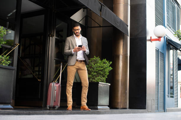 호텔 앞에서 택시를 기다리는 남자 - business suitcase men outdoors 뉴스 사진 이미지