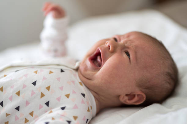 istock Newborn baby crying on bed 1211352138