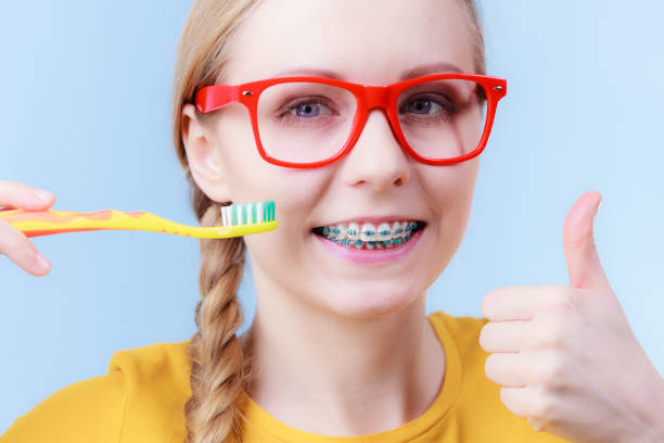 istock Woman smiling cleaning teeth with braces 1211352154
