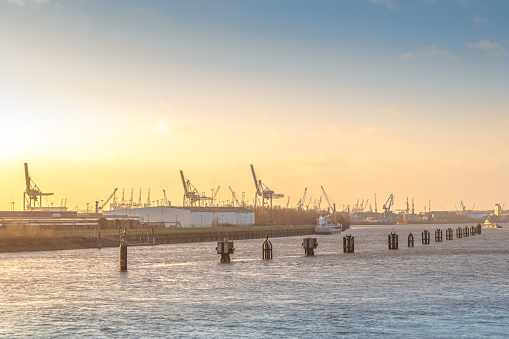 Industrial harbor of Hamburg from afar with Elbe river in focus, illuminated by the sun. Royalty free stock photo.
