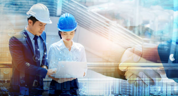 istock Two Asian people engineers are talking about work. Using a laptop to find information, systematic construction, 5G technology construction. Wearing a helmet helps prevent accidents in the workplace. 1211354083