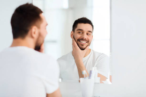 istock happy young man looking to mirror at home bathroom 1211354613