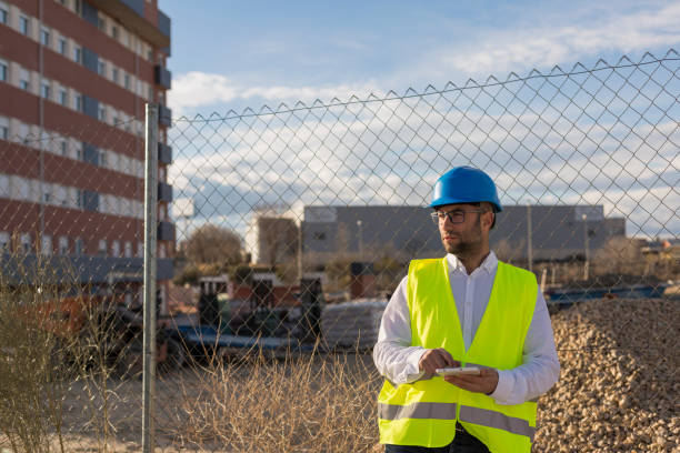 architekt lub inżynier człowiek za pomocą tabletu na placu budowy. koncepcja pracy. noszenie odzieży ochronnej - people in a row in a row business office worker zdjęcia i obrazy z banku zdjęć