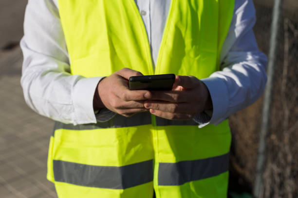 istock close up view of an Architect or Engineer man hands using mobile phone on the construction site. Job concept. Wearing protective clothes 1211355496
